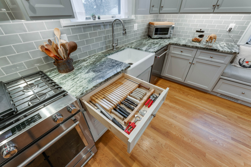 Inspiration for a small traditional l-shaped separate kitchen in Columbus with a farmhouse sink, shaker cabinets, green cabinets, granite benchtops, green splashback, stainless steel appliances, light hardwood floors, no island, brown floor and green benchtop.