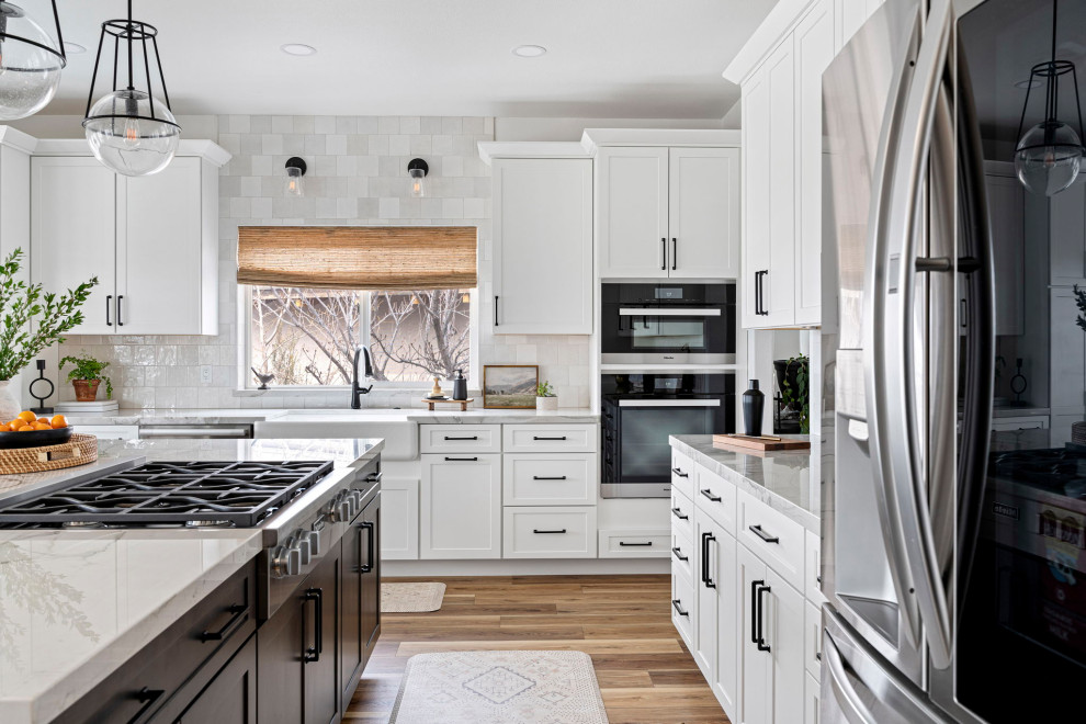 Inspiration for a transitional vinyl floor and brown floor kitchen remodel with a farmhouse sink, shaker cabinets, white cabinets, quartzite countertops, white backsplash and stainless steel appliances