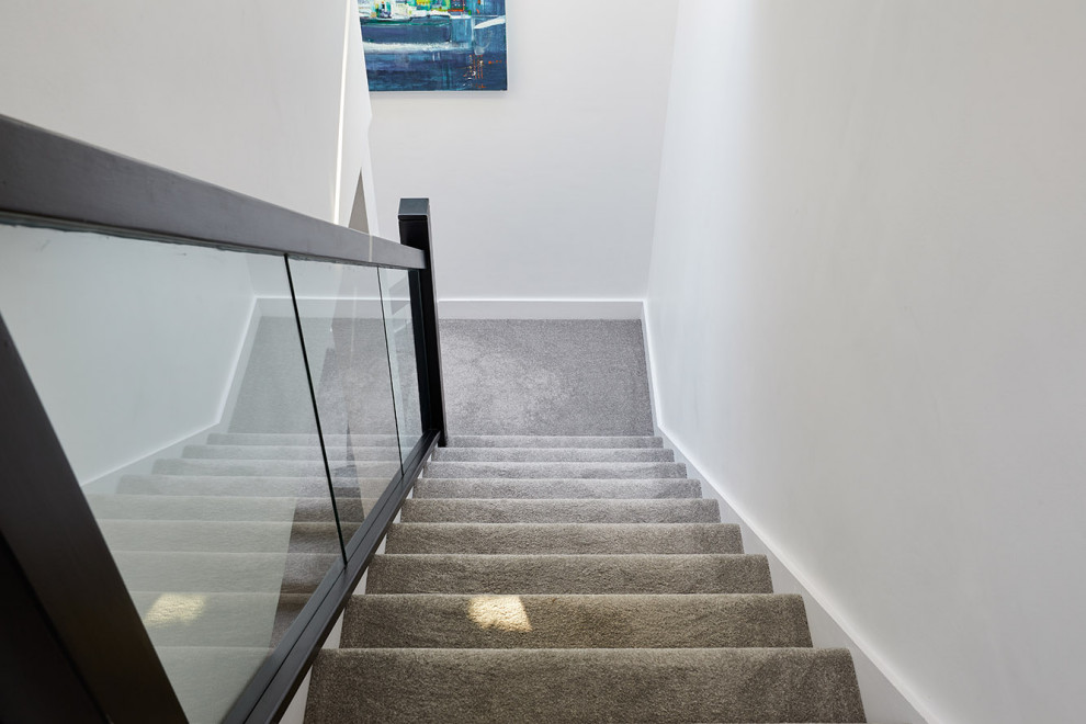 ロンドンにあるお手頃価格の小さなコンテンポラリースタイルのおしゃれな折り返し階段 (カーペット張りの蹴込み板、ガラスフェンス) の写真