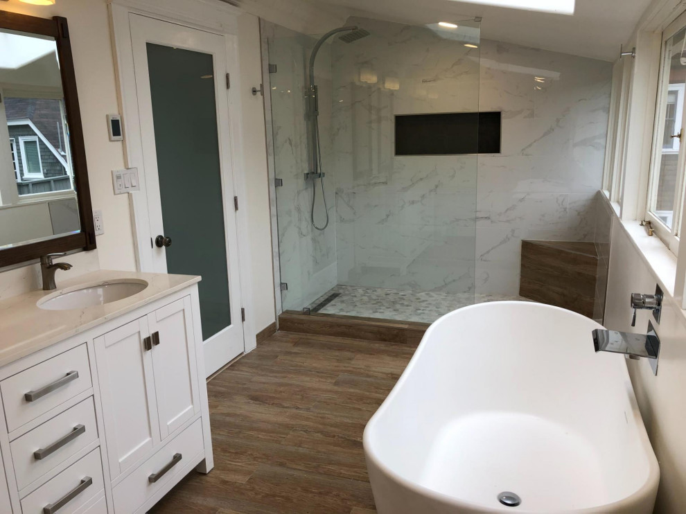 Inspiration for an ensuite bathroom in Other with white cabinets, a freestanding bath, a built-in shower, a one-piece toilet, white walls, light hardwood flooring, brown floors, an open shower, white worktops, a shower bench, double sinks, a freestanding vanity unit and a wood ceiling.