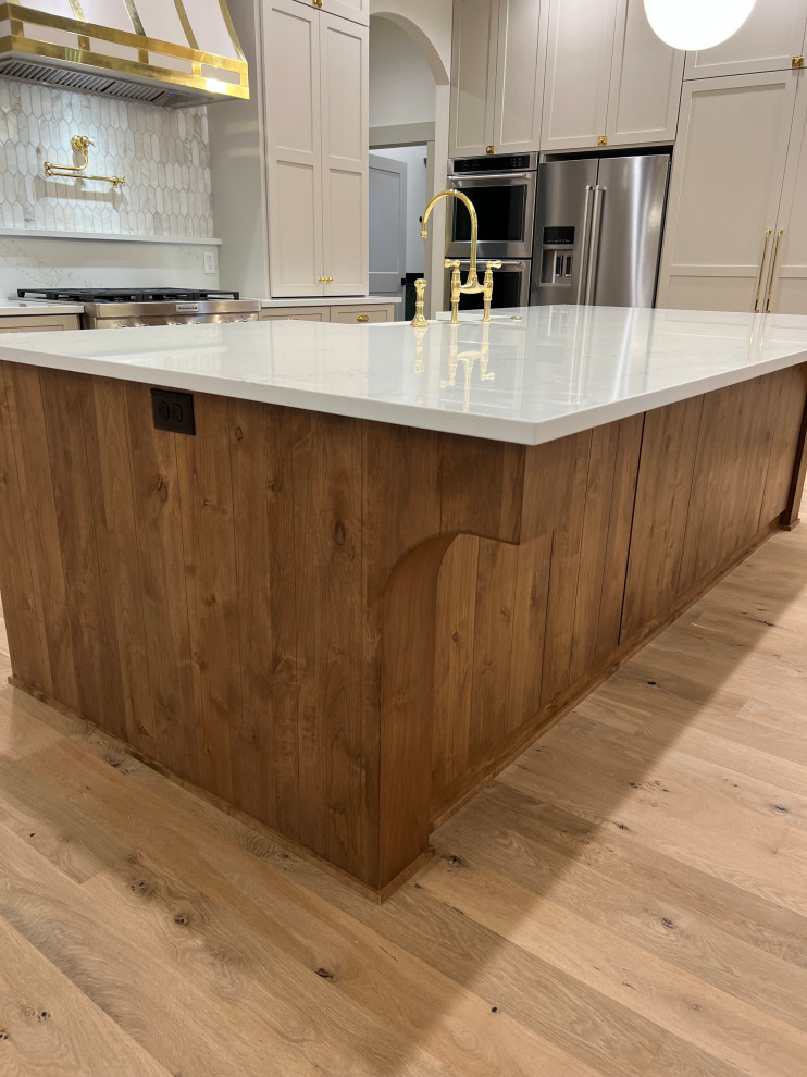 Large transitional l-shaped light wood floor and shiplap ceiling kitchen photo with a farmhouse sink, shaker cabinets, beige cabinets, quartz countertops, gray backsplash, marble backsplash, stainless steel appliances, an island and white countertops