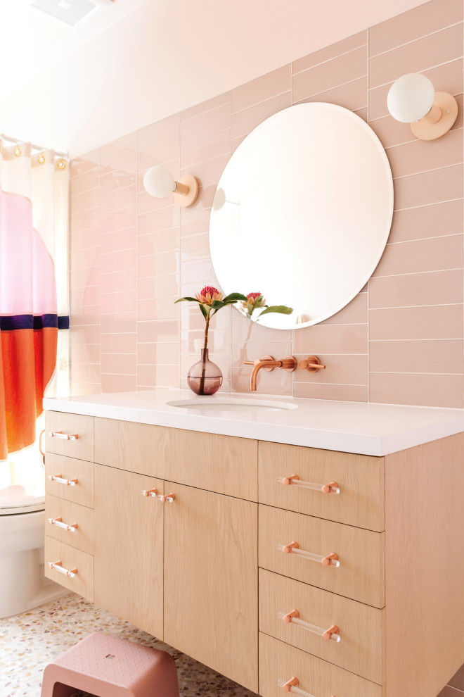 Foto på ett mellanstort funkis vit badrum för barn, med skåp i ljust trä, ett badkar i en alkov, en dusch/badkar-kombination, rosa kakel, glaskakel, ett undermonterad handfat, flerfärgat golv och dusch med duschdraperi