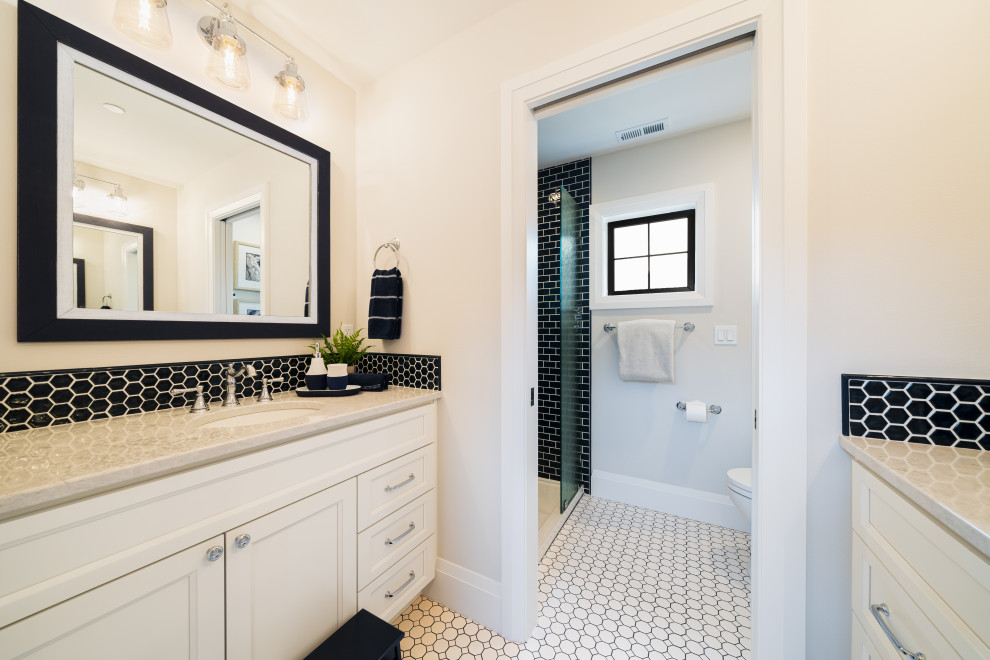 Photo of a mid-sized beach style bathroom in Seattle with recessed-panel cabinets, ceramic floors, an undermount sink, engineered quartz benchtops, a hinged shower door, grey benchtops, a single vanity and a built-in vanity.