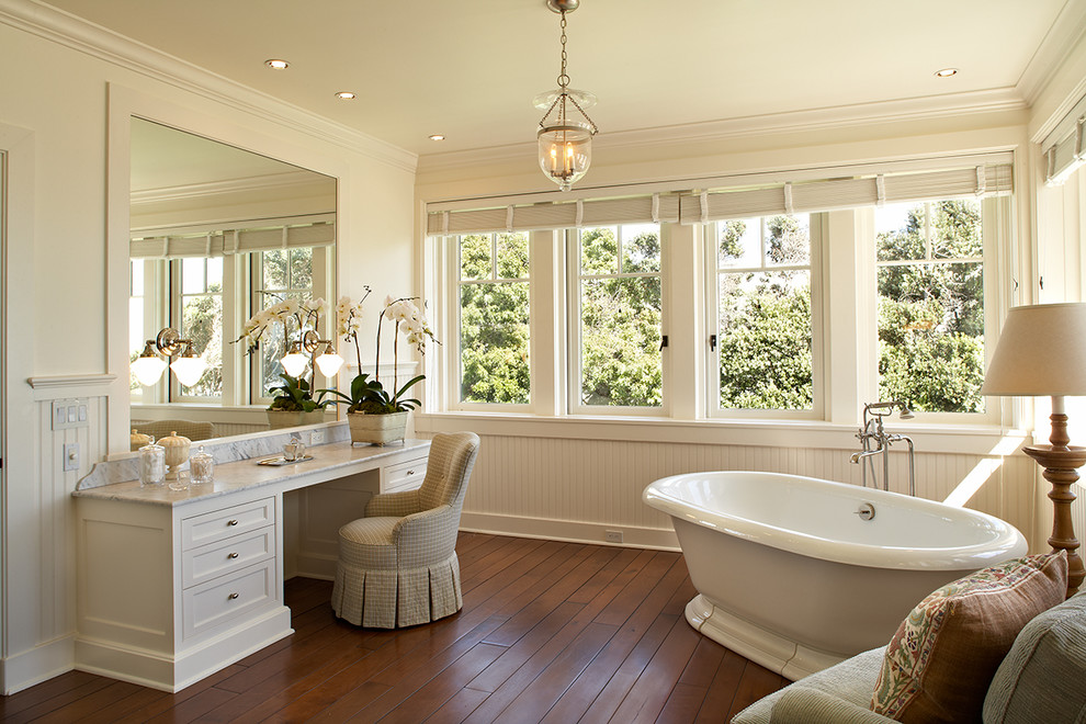 This is an example of a beach style bathroom in Los Angeles with recessed-panel cabinets, beige cabinets, a freestanding tub, beige walls and dark hardwood floors.