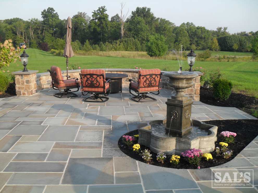This is an example of a large traditional backyard patio in Philadelphia with natural stone pavers.