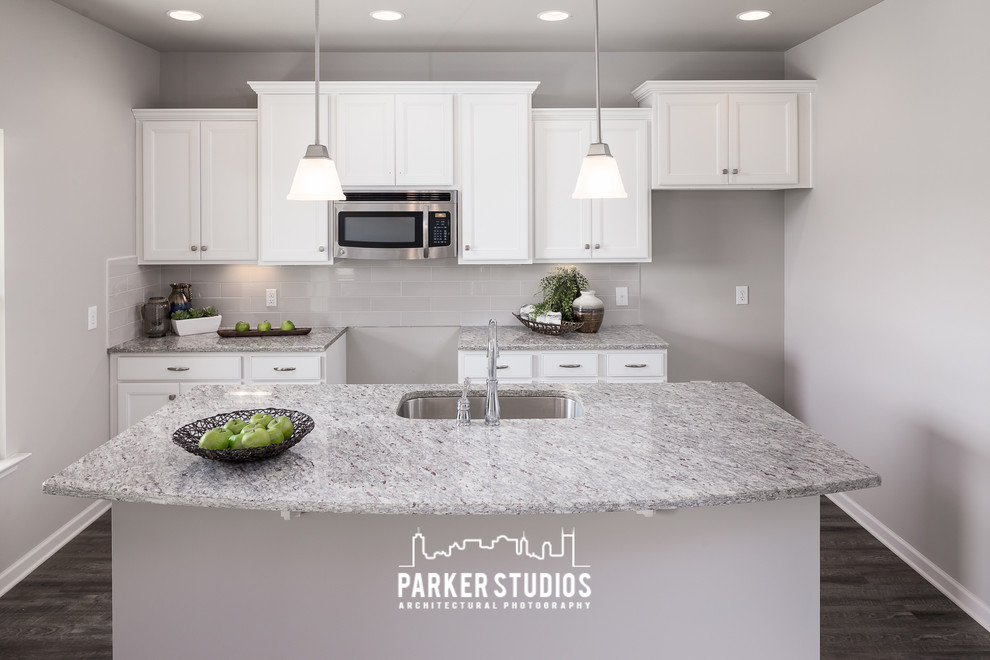 This is an example of a mid-sized traditional single-wall eat-in kitchen in Nashville with an undermount sink, recessed-panel cabinets, white cabinets, granite benchtops, grey splashback, glass tile splashback, stainless steel appliances, dark hardwood floors and with island.