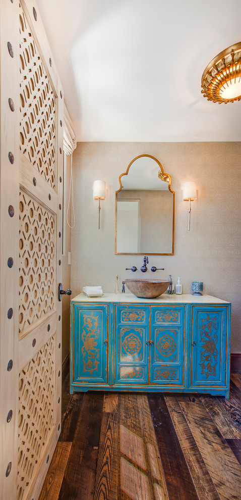 Inspiration for a mid-sized mediterranean powder room in Los Angeles with a vessel sink, furniture-like cabinets, blue cabinets, beige walls and medium hardwood floors.