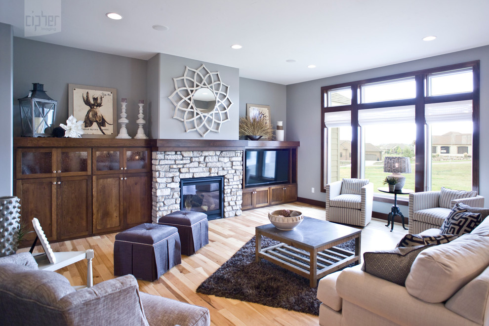 Large country formal open concept living room in Other with light hardwood floors, a standard fireplace, a stone fireplace surround, a built-in media wall, grey walls and yellow floor.