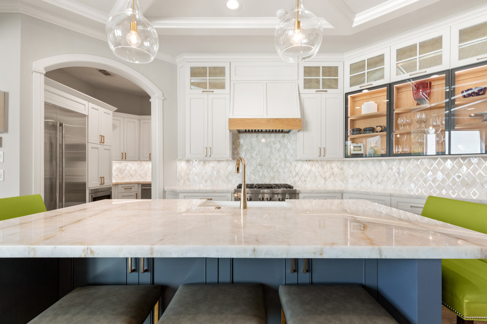 Large transitional single-wall light wood floor and brown floor eat-in kitchen photo in Houston with a farmhouse sink, recessed-panel cabinets, white cabinets, quartzite countertops, white backsplash, mosaic tile backsplash, stainless steel appliances, an island and white countertops