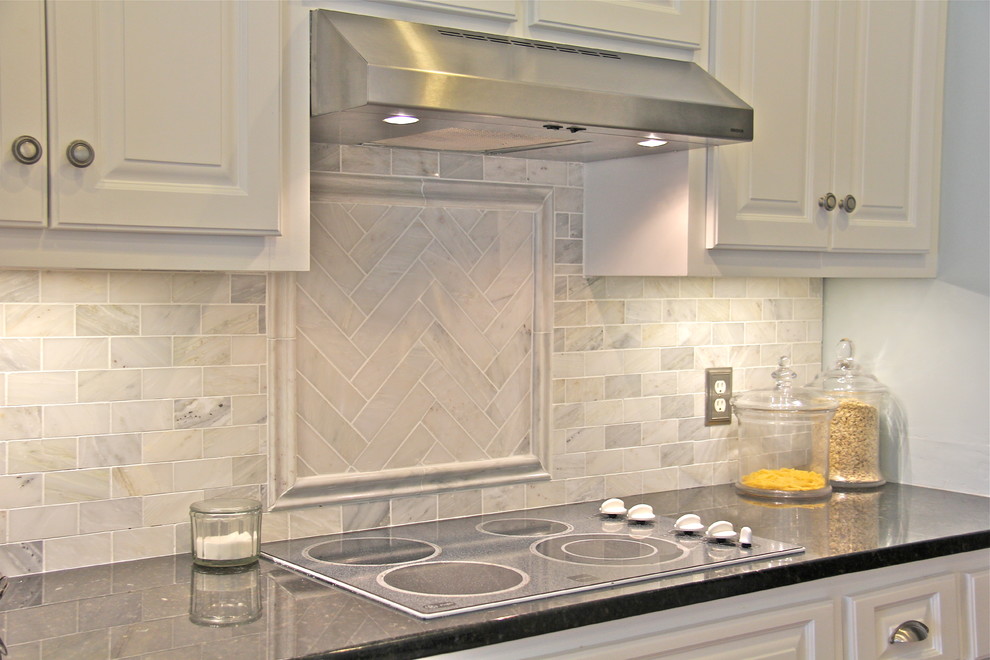 Enclosed kitchen - mid-sized coastal u-shaped medium tone wood floor enclosed kitchen idea with raised-panel cabinets, white cabinets, granite countertops, white backsplash, subway tile backsplash, stainless steel appliances and an undermount sink