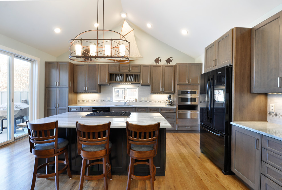 This is an example of a large country l-shaped kitchen in DC Metro with an undermount sink, recessed-panel cabinets, granite benchtops, medium hardwood floors and with island.