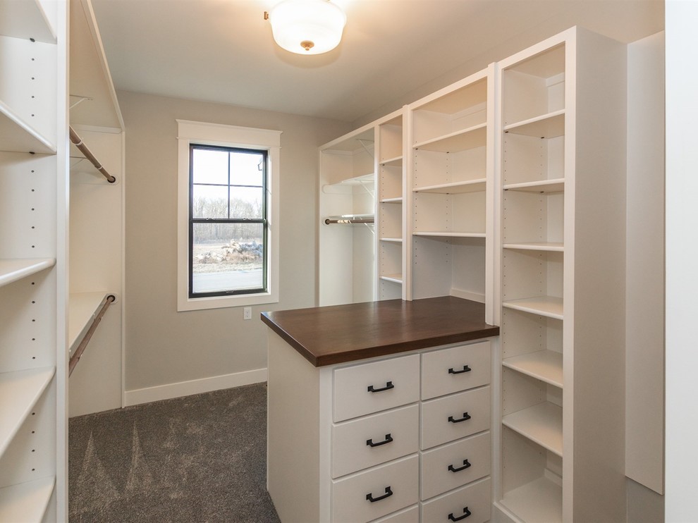 Large country gender-neutral walk-in wardrobe in Indianapolis with shaker cabinets, white cabinets, carpet and grey floor.