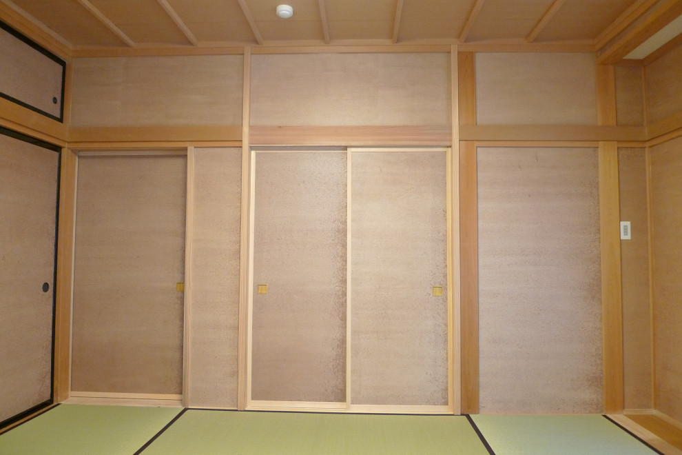 This is an example of an expansive asian guest bedroom in Other with beige walls, tatami floors, wood and wallpaper.