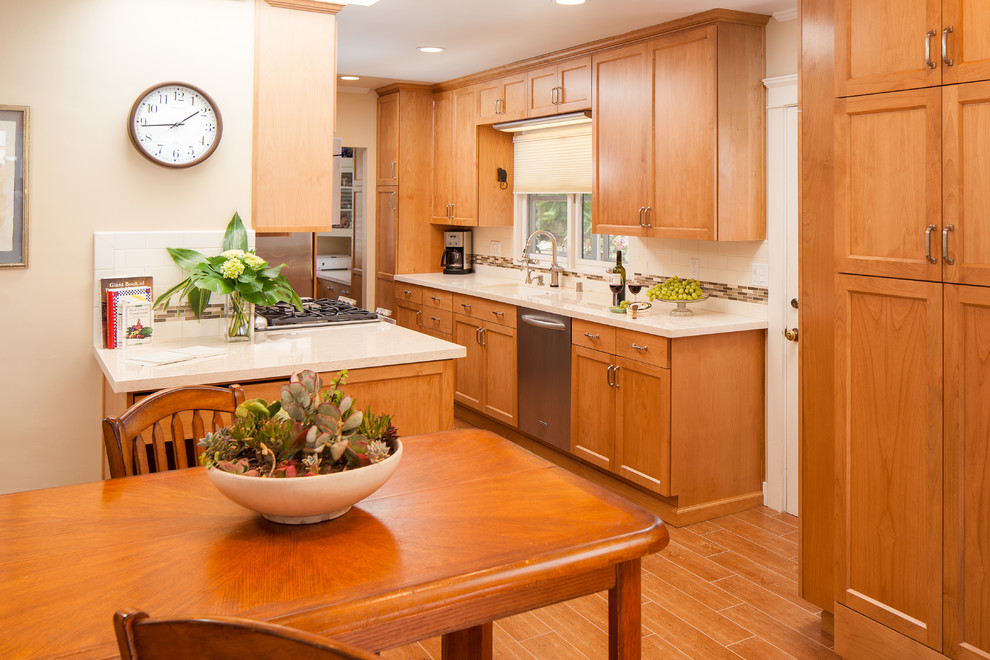 This is an example of a large traditional galley separate kitchen in San Diego with an undermount sink, shaker cabinets, medium wood cabinets, quartz benchtops, beige splashback, ceramic splashback, stainless steel appliances, porcelain floors, no island and brown floor.