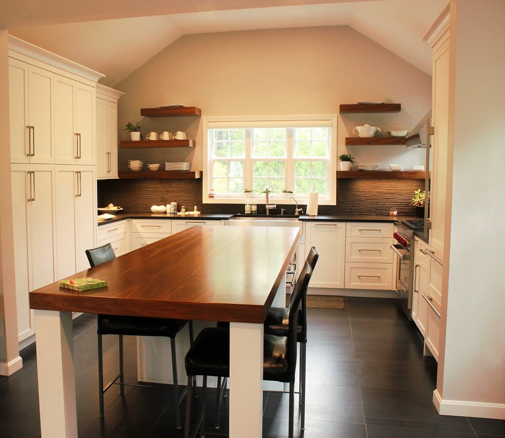 Inspiration for a mid-sized country u-shaped eat-in kitchen in Boston with black floor, a farmhouse sink, panelled appliances, ceramic floors, shaker cabinets, white cabinets, solid surface benchtops, black splashback, porcelain splashback and with island.