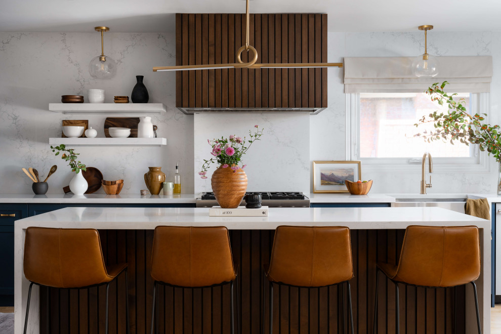 Example of a mid-sized transitional l-shaped medium tone wood floor and beige floor eat-in kitchen design in Toronto with a farmhouse sink, shaker cabinets, blue cabinets, quartz countertops, white backsplash, quartz backsplash, stainless steel appliances, an island and white countertops