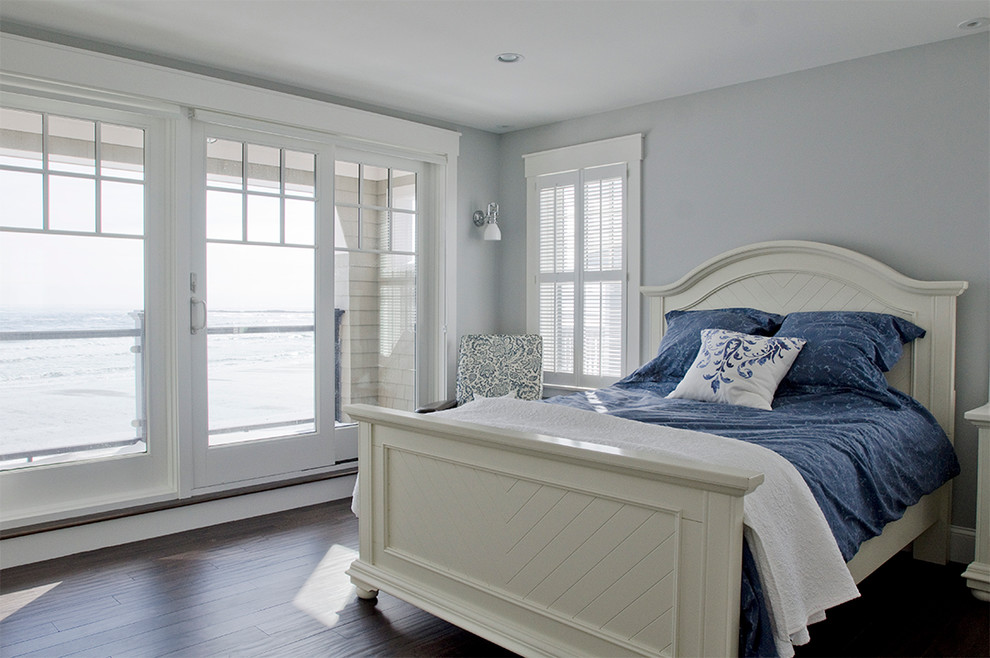 This is an example of a large beach style master bedroom in Portland Maine with blue walls, dark hardwood floors and no fireplace.