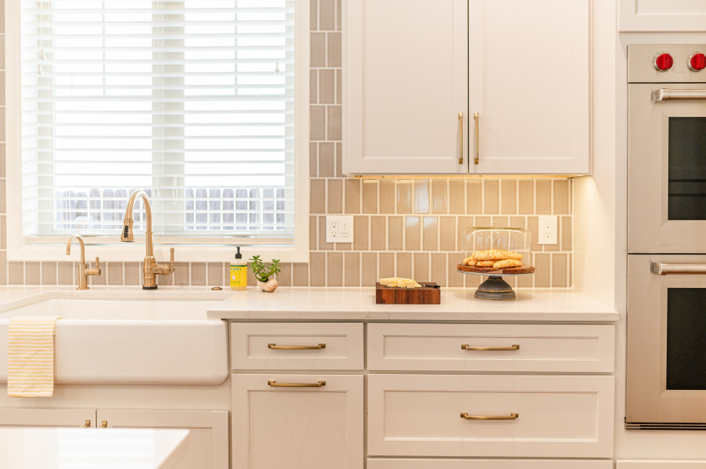 Inspiration for a large transitional l-shaped dark wood floor and brown floor open concept kitchen remodel in Denver with a farmhouse sink, shaker cabinets, beige cabinets, quartz countertops, beige backsplash, ceramic backsplash, stainless steel appliances, an island and white countertops