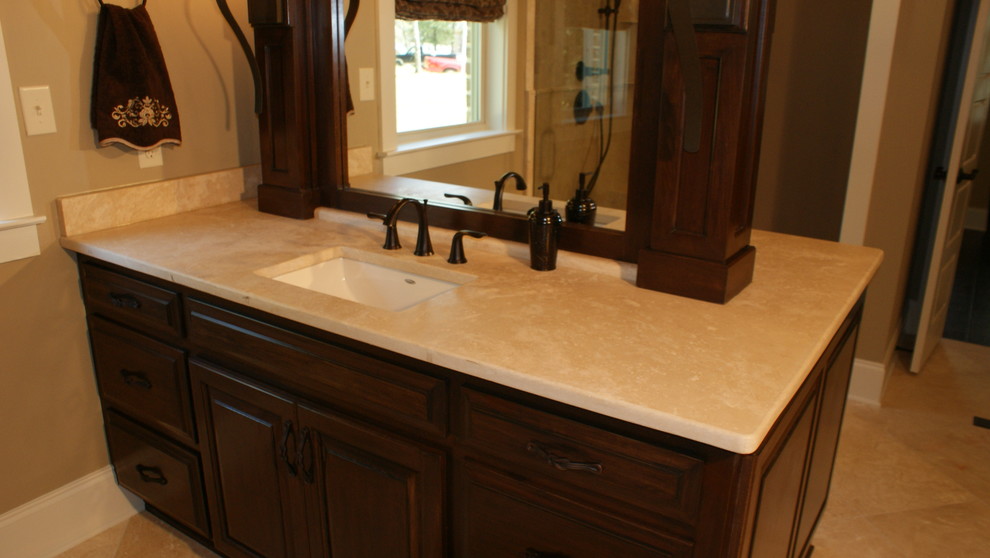 Photo of a mid-sized traditional master bathroom in Miami with raised-panel cabinets, dark wood cabinets, beige tile, beige walls, travertine floors, a wall-mount sink and limestone benchtops.