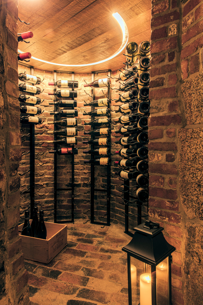 This is an example of a small eclectic wine cellar in Boston with brick floors and storage racks.