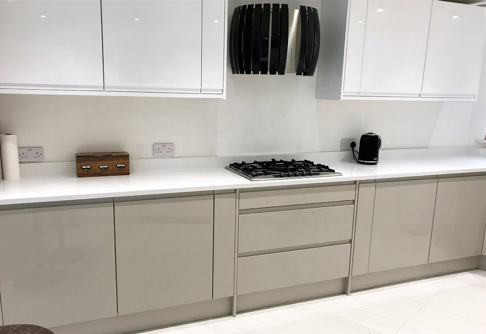 This is an example of a mid-sized modern l-shaped eat-in kitchen in Essex with flat-panel cabinets, with island and white floor.