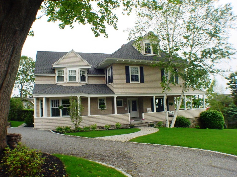 Large traditional two-storey beige house exterior in Boston with wood siding, a gable roof and a shingle roof.