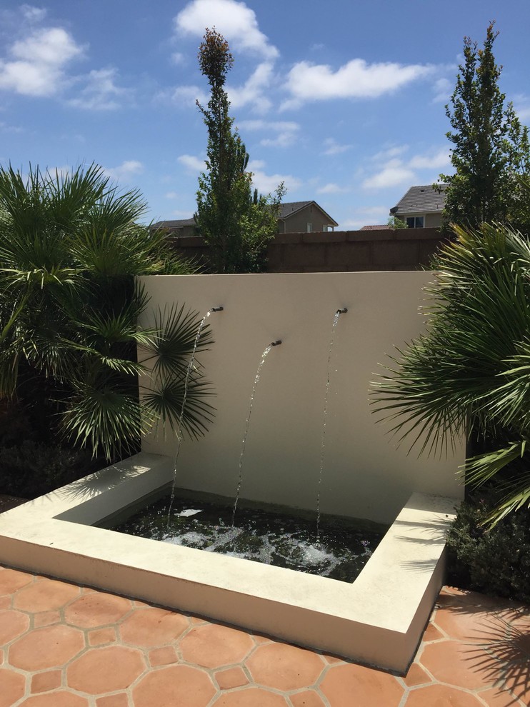 Patio fountain - mid-sized modern backyard tile patio fountain idea in Orange County with no cover