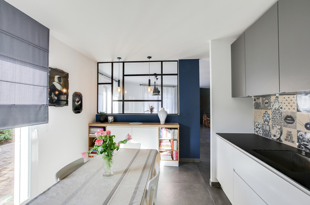 Inspiration for an eclectic kitchen with an undermount sink, beaded inset cabinets, white cabinets, granite benchtops, multi-coloured splashback, ceramic splashback, stainless steel appliances, ceramic floors, grey floor and black benchtop.