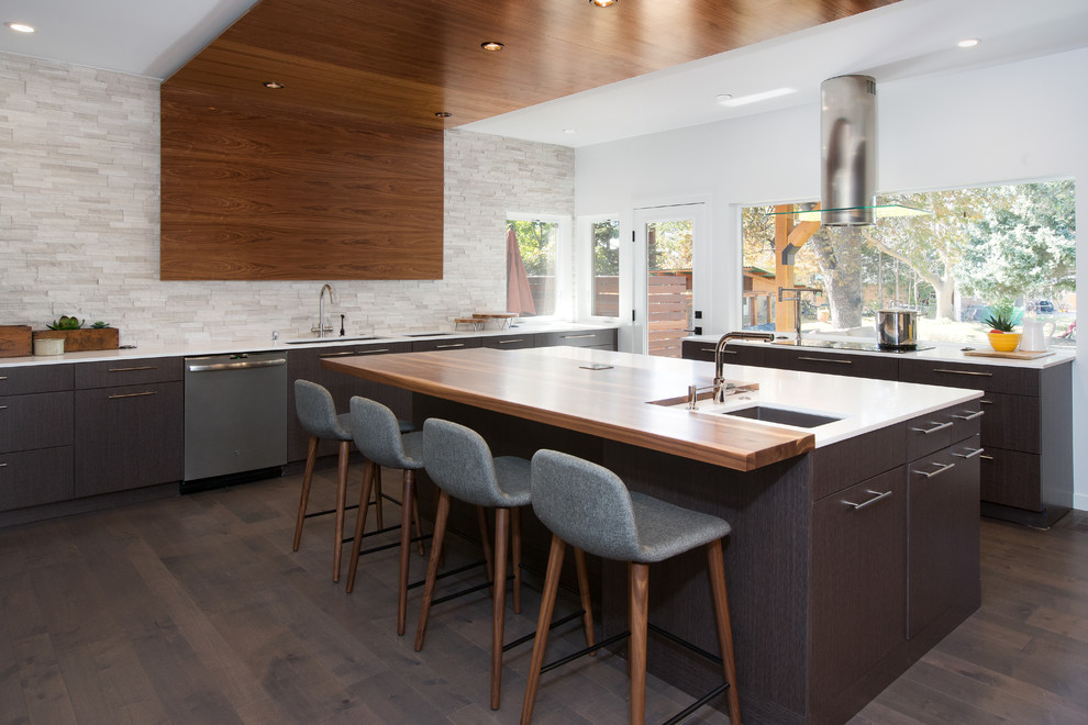 Large trendy u-shaped dark wood floor and brown floor kitchen photo in Denver with flat-panel cabinets, quartz countertops, stainless steel appliances, an island, white countertops, an undermount sink, brown cabinets, gray backsplash and stone tile backsplash