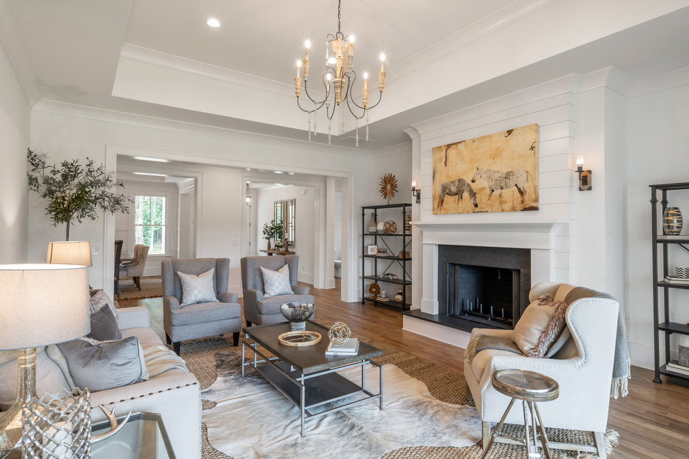 Design ideas for a country family room in Atlanta with white walls, medium hardwood floors, a standard fireplace and brown floor.