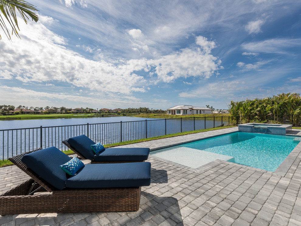 Photo of a mid-sized beach style backyard rectangular lap pool in Miami with a hot tub and brick pavers.