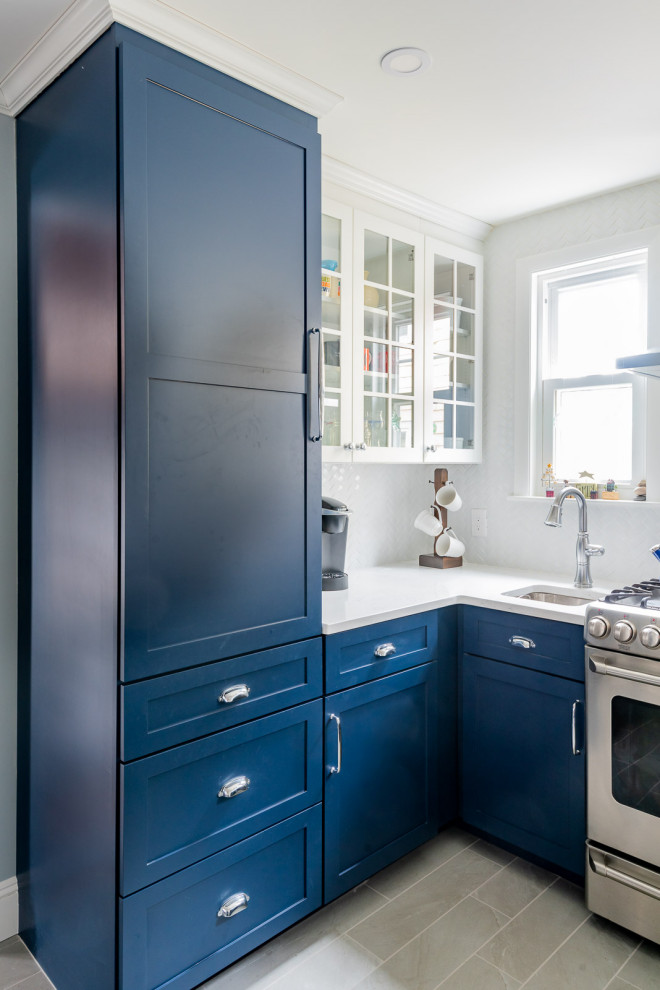 This is an example of a medium sized classic u-shaped kitchen/diner in Boston with a submerged sink, shaker cabinets, blue cabinets, engineered stone countertops, white splashback, metro tiled splashback, stainless steel appliances, porcelain flooring, a breakfast bar, grey floors and white worktops.