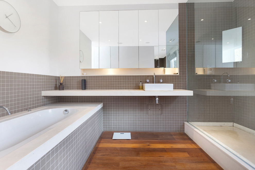 Contemporary master bathroom in London with white cabinets, a drop-in tub, an alcove shower, white walls, medium hardwood floors, a vessel sink, brown floor and white benchtops.