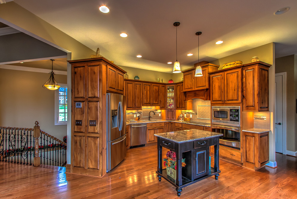 Mountain style kitchen photo with raised-panel cabinets, granite countertops, subway tile backsplash and an island