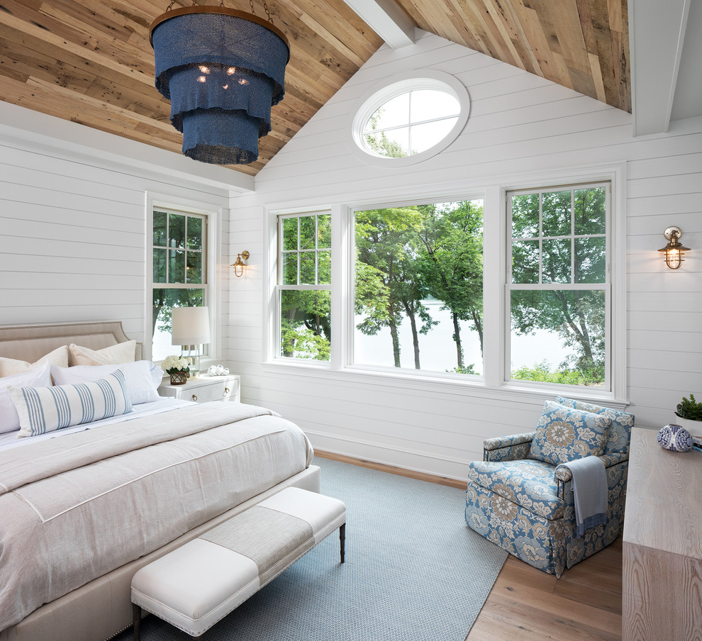 This is an example of a beach style master bedroom in Minneapolis with white walls, light hardwood floors and no fireplace.