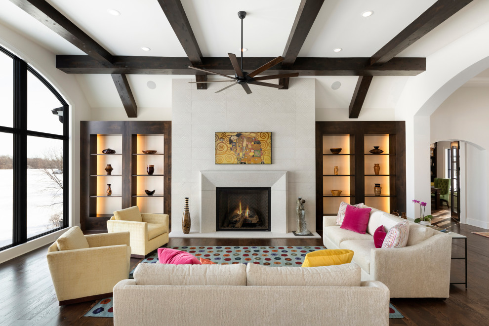 Inspiration for a large transitional open concept family room in Minneapolis with white walls, dark hardwood floors, a standard fireplace, a tile fireplace surround, brown floor, exposed beam and vaulted.