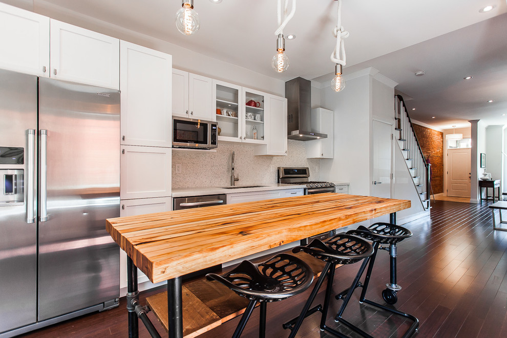 Photo of a mid-sized transitional single-wall eat-in kitchen in Toronto with a double-bowl sink, shaker cabinets, white cabinets, quartz benchtops, white splashback, mosaic tile splashback, stainless steel appliances, dark hardwood floors and with island.