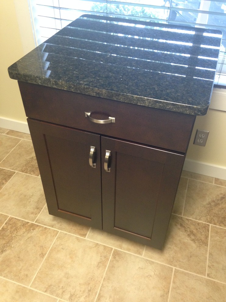 Mid-sized transitional l-shaped porcelain tile enclosed kitchen photo with an undermount sink, shaker cabinets, dark wood cabinets, granite countertops, beige backsplash, stone tile backsplash, stainless steel appliances and an island