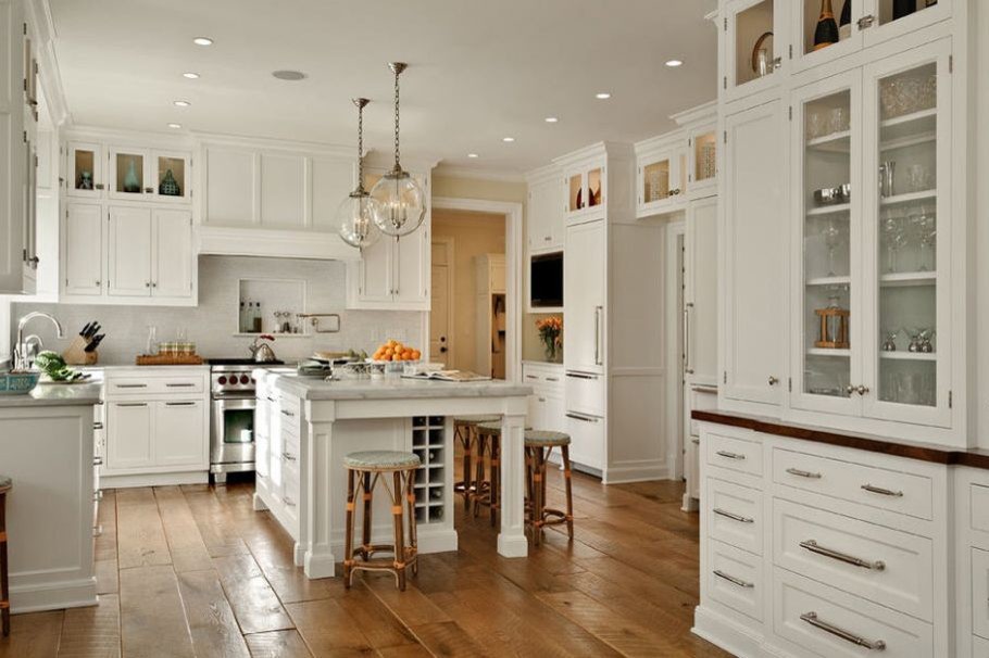 Example of a large transitional u-shaped medium tone wood floor and brown floor kitchen design in DC Metro with a farmhouse sink, recessed-panel cabinets, white cabinets, quartzite countertops, white backsplash, paneled appliances, an island and white countertops