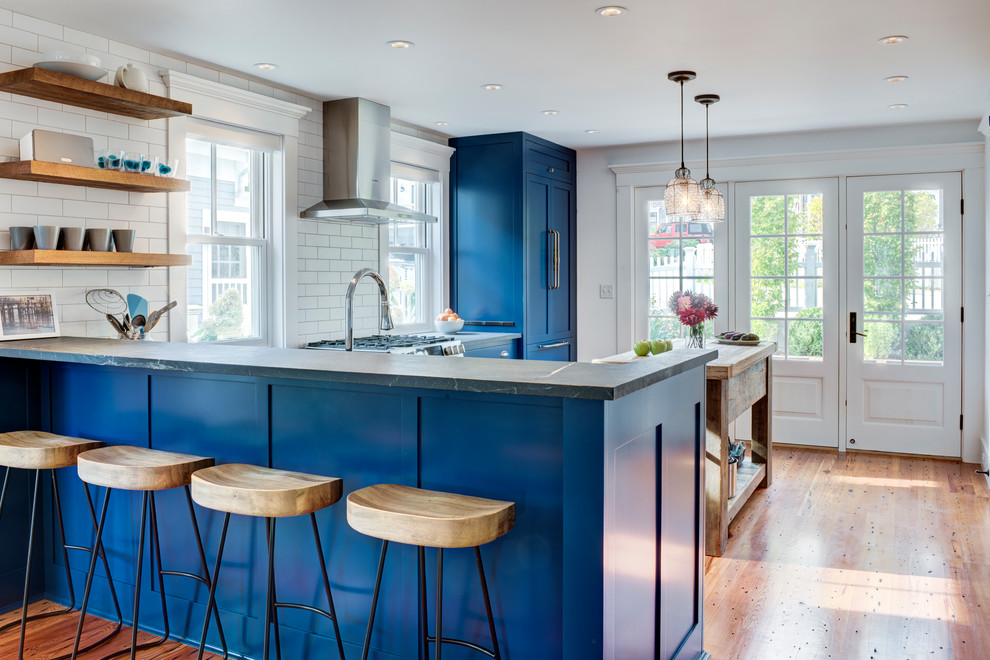 This is an example of a country u-shaped kitchen in Boston with shaker cabinets, blue cabinets, panelled appliances, medium hardwood floors, with island, brown floor and grey benchtop.