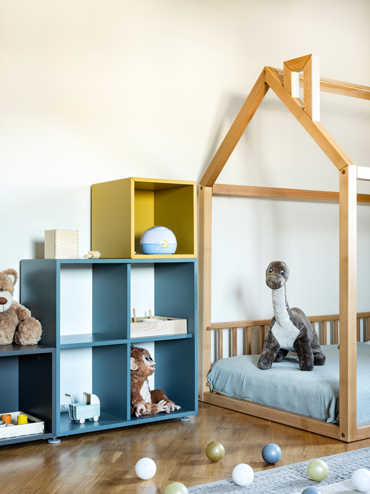 Esempio di una grande cameretta per bambini da 1 a 3 anni design con pareti beige, pavimento in legno massello medio e pavimento marrone