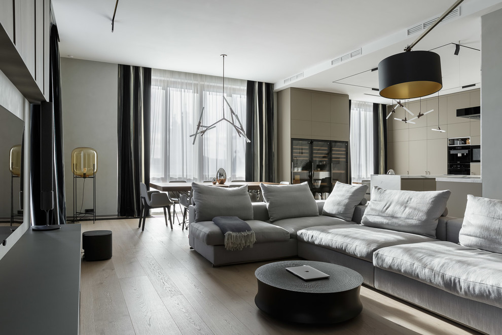 This is an example of a contemporary formal open concept living room in Saint Petersburg with white walls, light hardwood floors, a wall-mounted tv and beige floor.