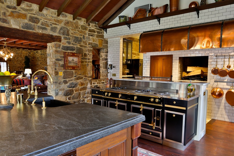 Photo of a country kitchen in New York with a farmhouse sink, medium wood cabinets, white splashback, subway tile splashback and black appliances.