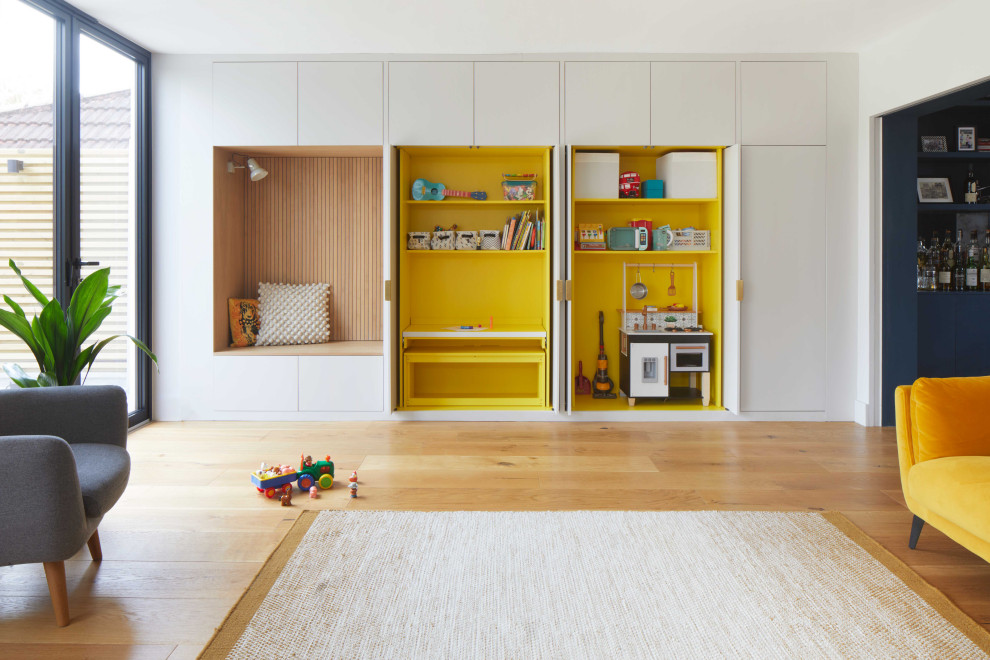 Стильный дизайн: большая открытая гостиная комната в современном стиле с с книжными шкафами и полками, желтыми стенами, паркетным полом среднего тона, панелями на части стены и акцентной стеной без камина - последний тренд