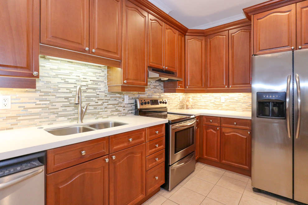 Enclosed kitchen - mid-sized transitional u-shaped porcelain tile and beige floor enclosed kitchen idea in Toronto with an undermount sink, recessed-panel cabinets, brown cabinets, quartz countertops, beige backsplash, mosaic tile backsplash, stainless steel appliances and a peninsula