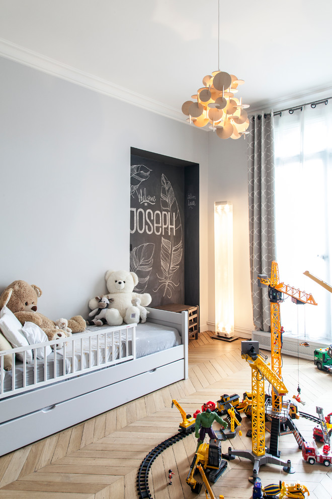 Mid-sized contemporary gender-neutral kids' bedroom in Paris with grey walls, brown floor and medium hardwood floors for kids 4-10 years old.