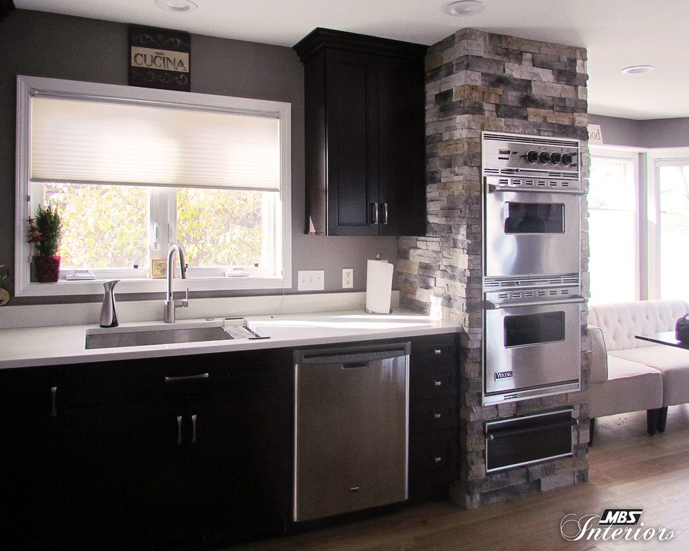 Inspiration for a large transitional l-shaped light wood floor eat-in kitchen remodel with an undermount sink, recessed-panel cabinets, dark wood cabinets, quartz countertops, stainless steel appliances and an island