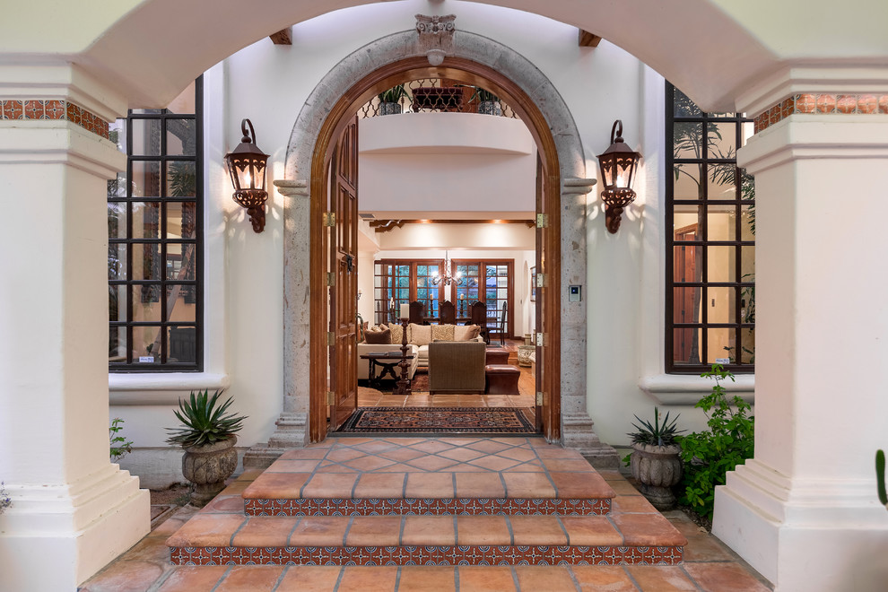 Design ideas for a mid-sized mediterranean front door in Las Vegas with white walls, terra-cotta floors and a double front door.