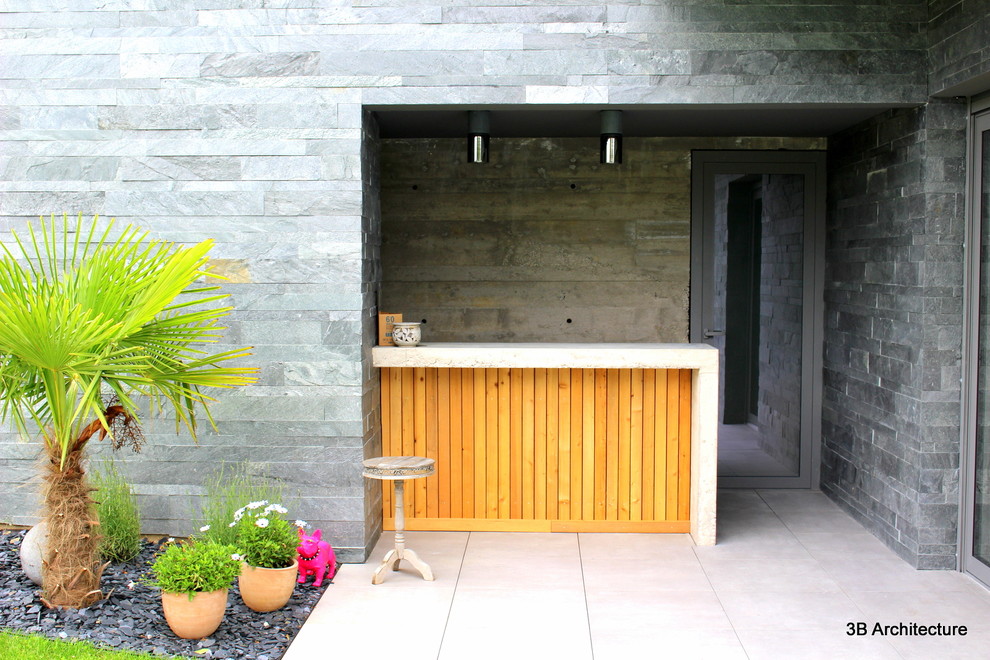 Aménagement d'une terrasse latérale contemporaine de taille moyenne avec une cuisine d'été, du carrelage et une extension de toiture.