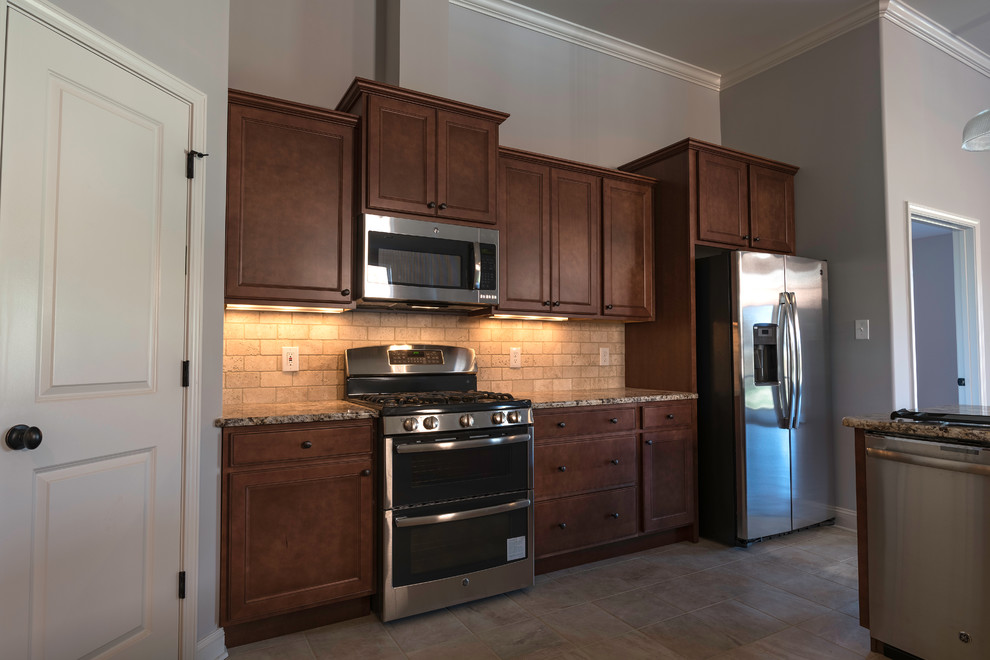 Open concept kitchen - mid-sized transitional l-shaped travertine floor open concept kitchen idea with an undermount sink, shaker cabinets, medium tone wood cabinets, granite countertops, beige backsplash, stone tile backsplash, stainless steel appliances and an island